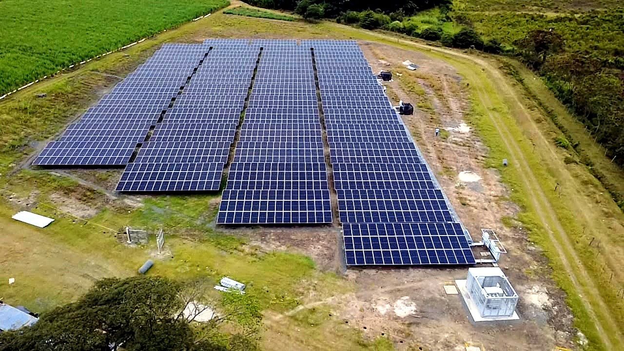 Vista aérea de una planta solar fotovoltaica en piso rodeada de cultivos